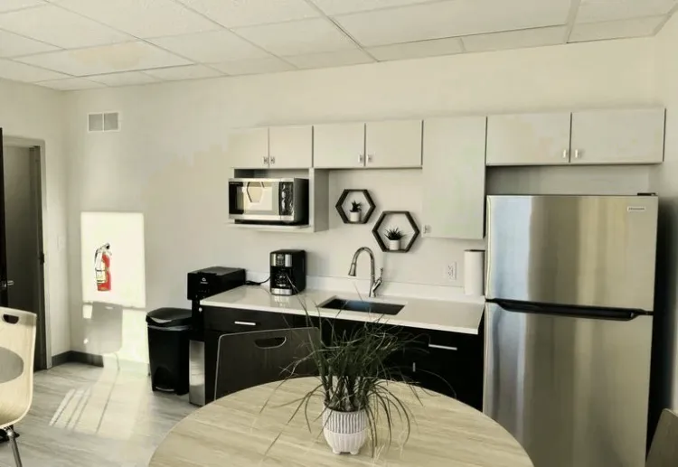 The office kitchen at Changes Counseling: cabinets, a sink, a coffee maker and a microwave, with a round table and a plant in the foreground.