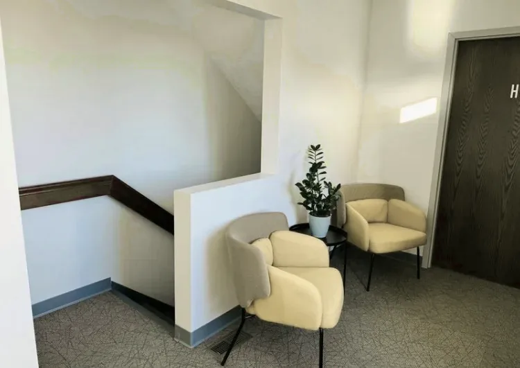 A quiet corner of the Changes Counseling waiting area: two upholstered armchairs either side of a small round table with a potted plant, beside the stairwell.